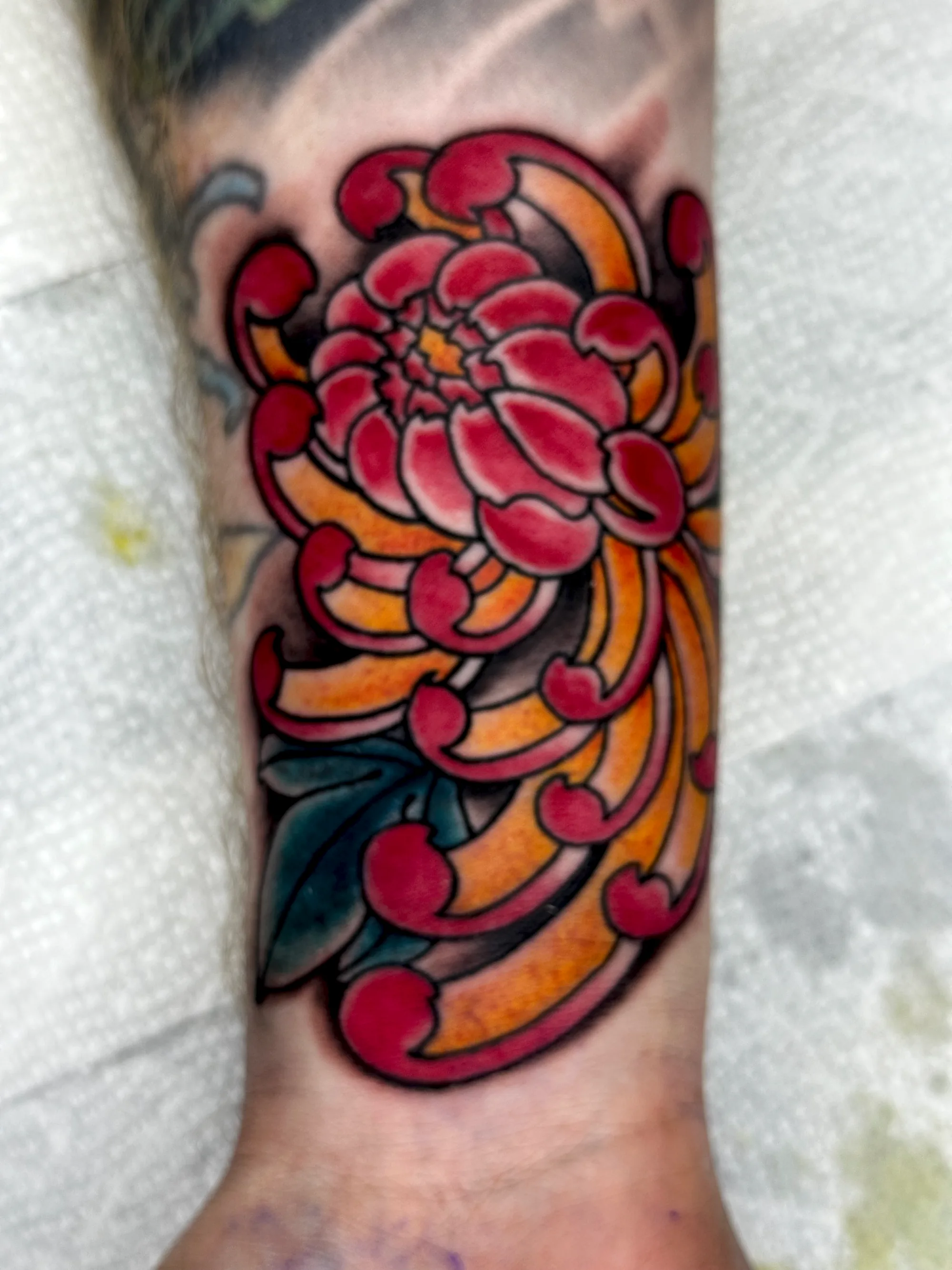 Floral colour forearm sleeve tattoo with red and yellow flowers by Nate at Village Tattoo Company London Ontario