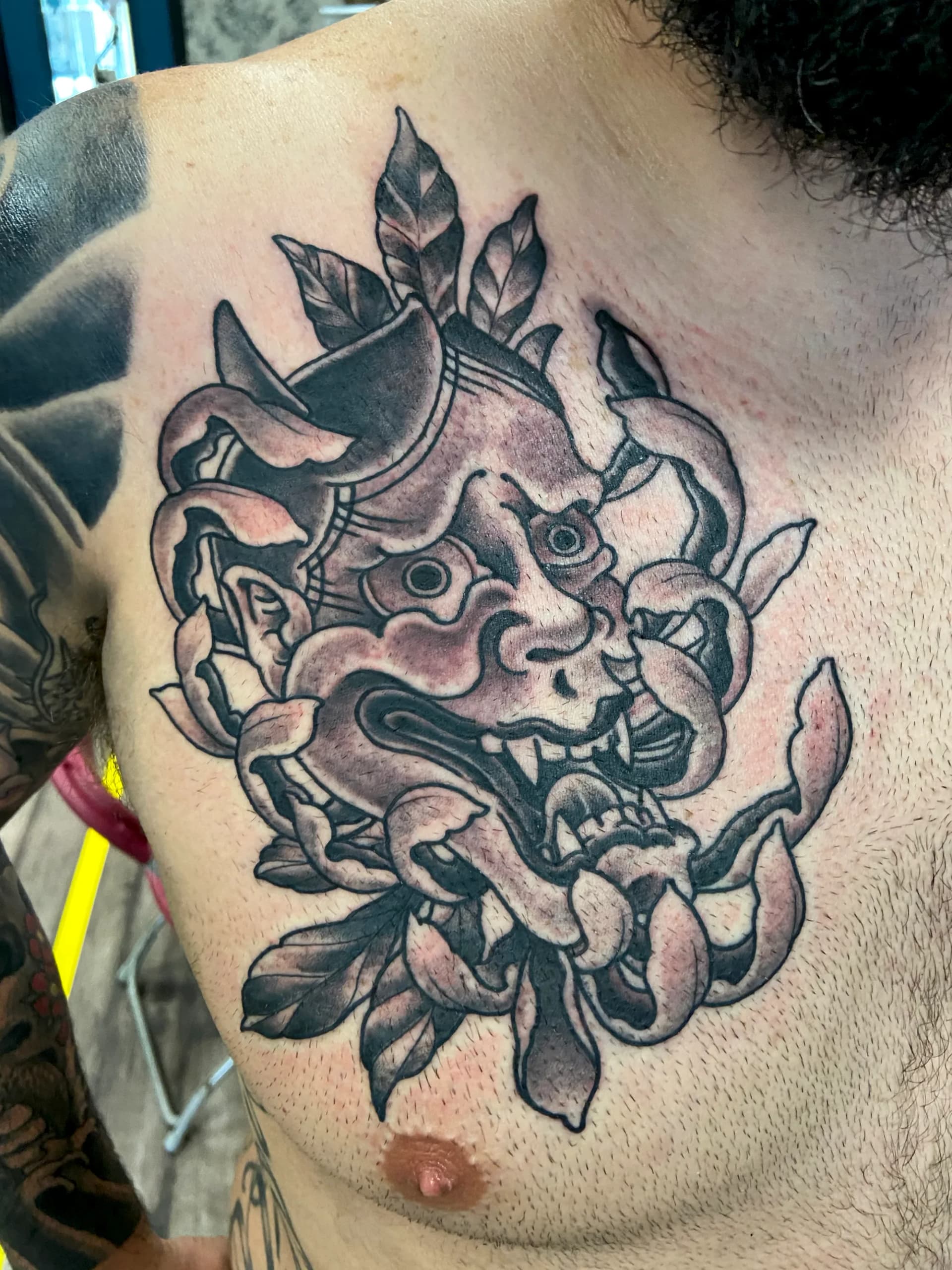 Hannya mask with flower black and grey chest tattoo by Nate at Village Tattoo Company London Ontario