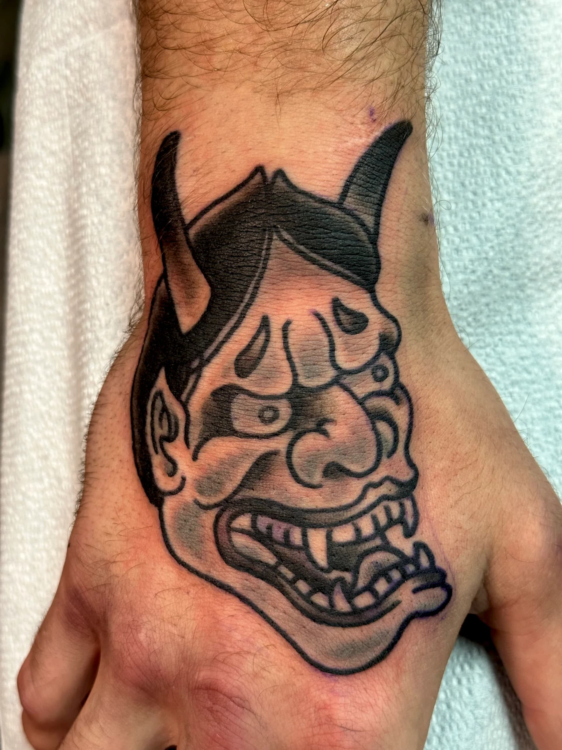 Hannya mask on hand Japanese colour tattoo by Nate at Village Tattoo Company London Ontario