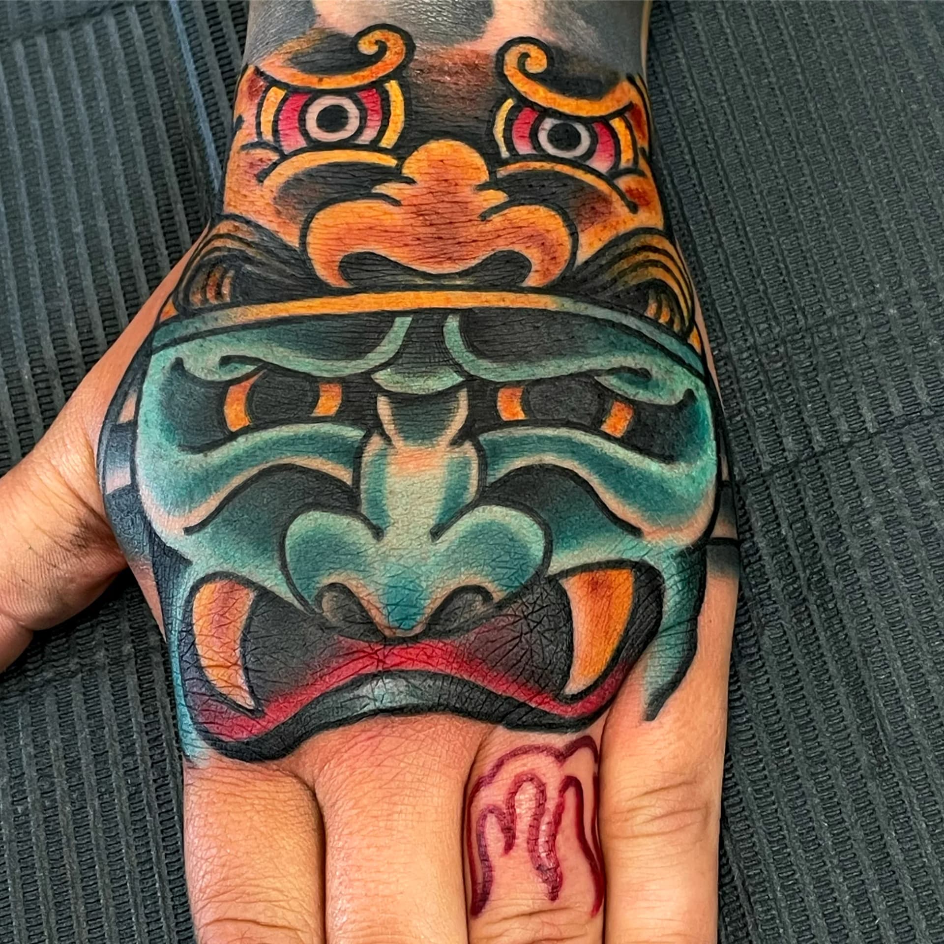 Japanese mask hand tattoo by Nate at Village Tattoo Company London Ontario