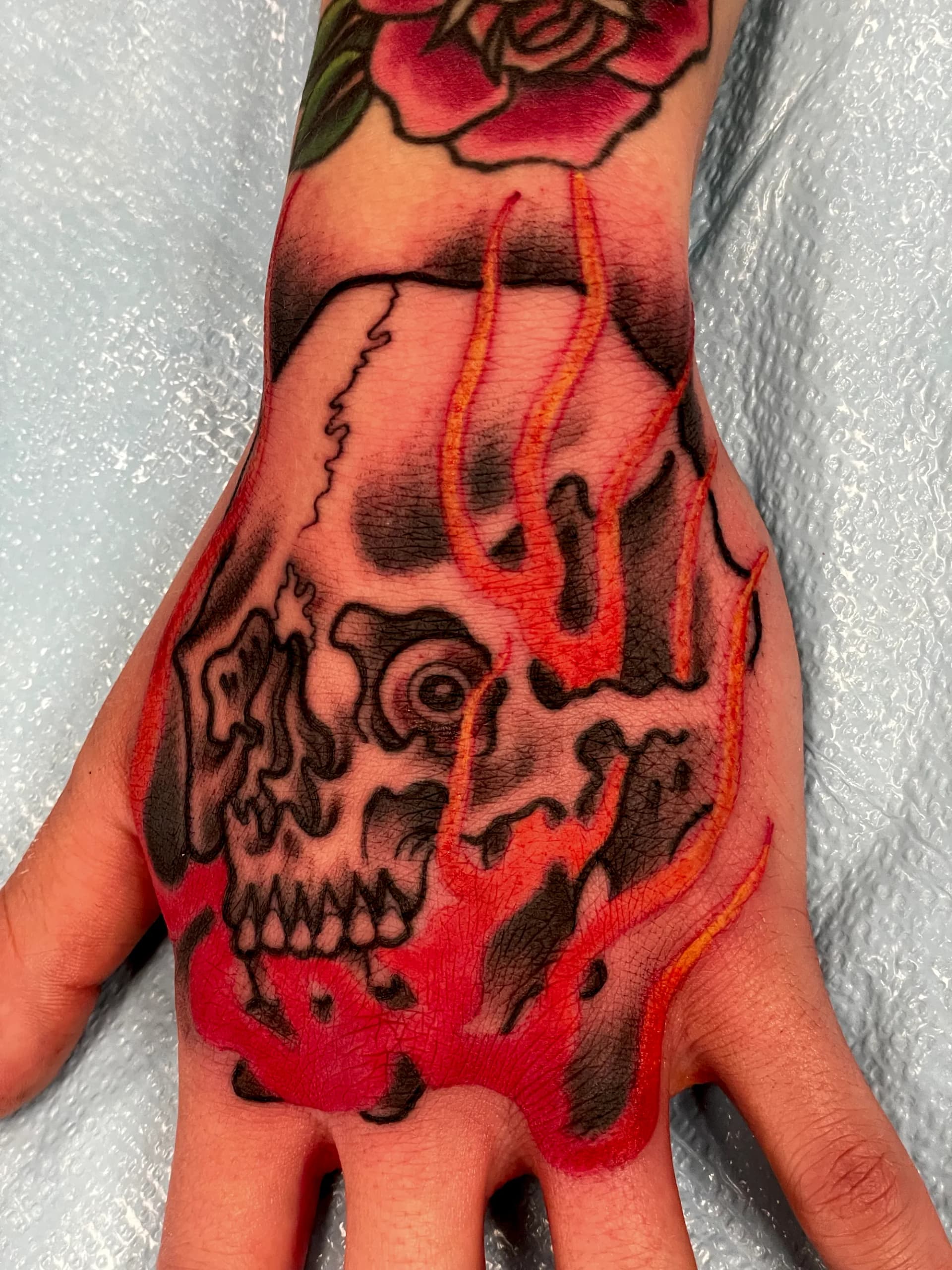 Skull with flames hand traditional tattoo by Nate at Village Tattoo Company London Ontario