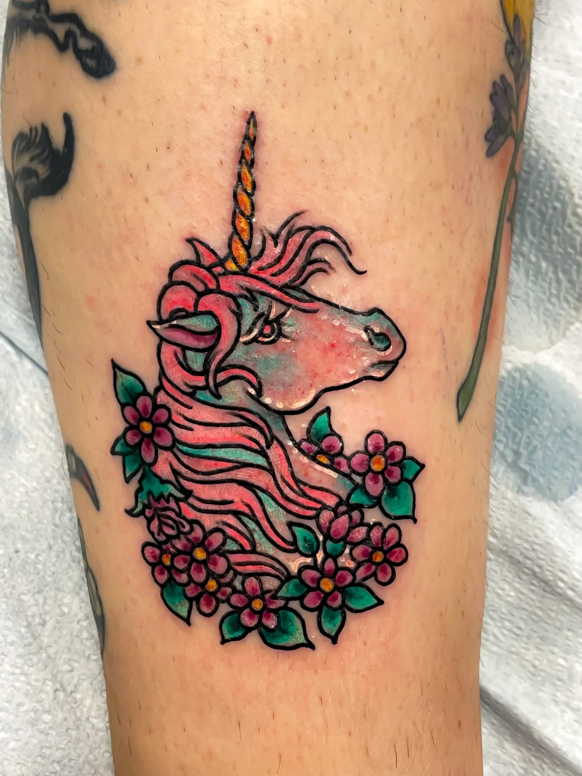 Unicorn traditional colour tattoo with flowers by Nate at Village Tattoo Company London Ontario