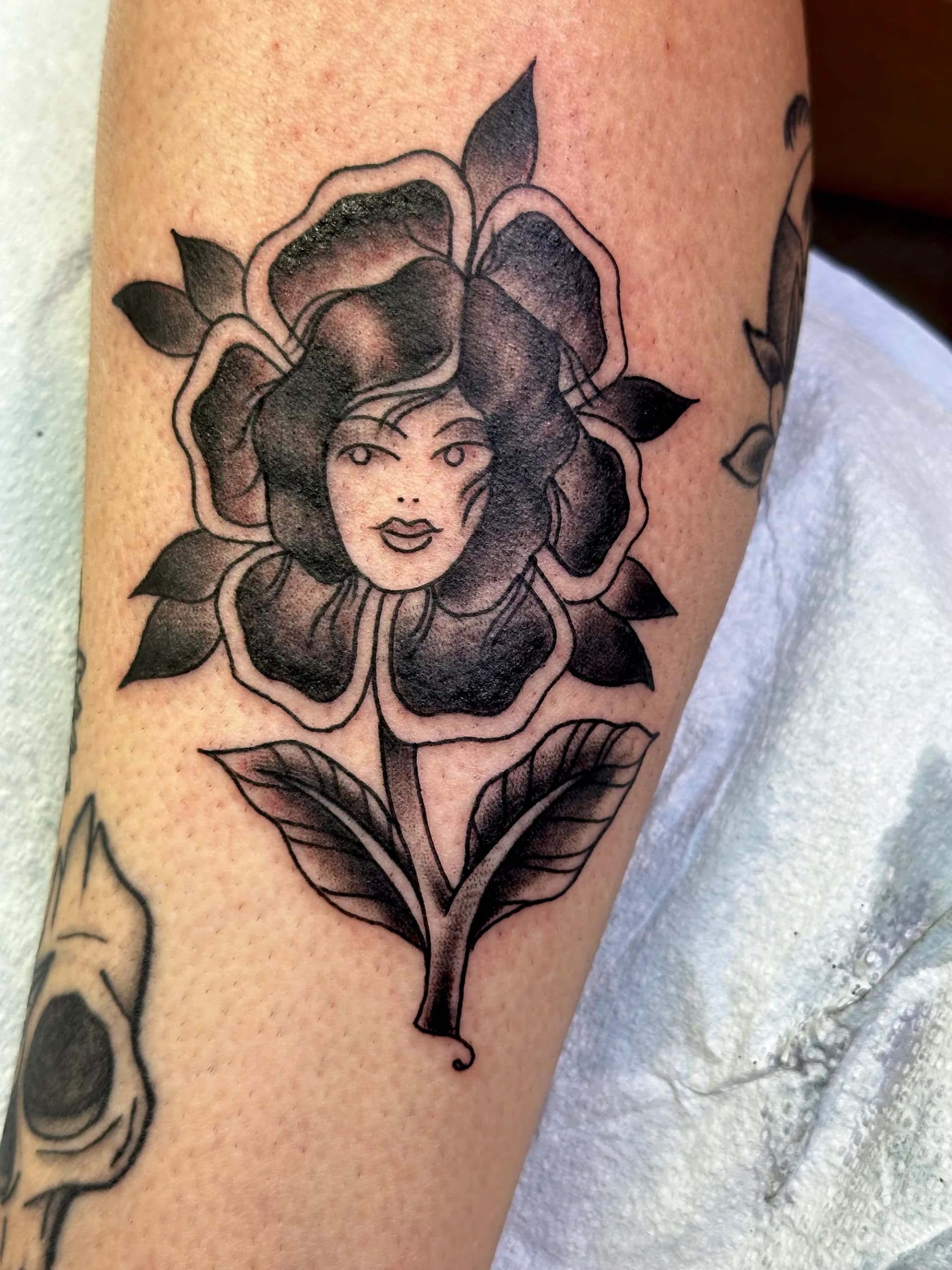 Woman portrait stylized upper arm tattoo with flowers by Nate at Village Tattoo Company London Ontario